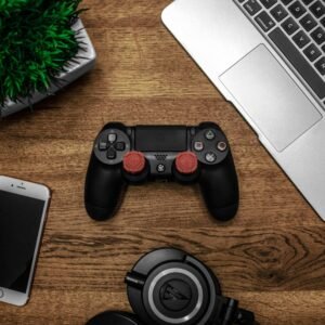 A flat lay photo showcasing a gaming console, laptop, smartphone, and headphones on a wooden tabletop.